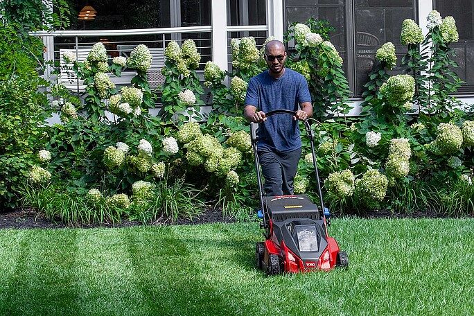 Watermaster Irrigation Supply Inc. | What to Look for When Buying Lawn Equipment for Sale Locally Person mowing a green lawn with a red lawn mower in a garden